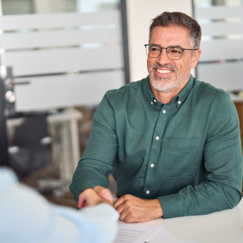 Happy mature business man lawyer and client making deal with handshake.